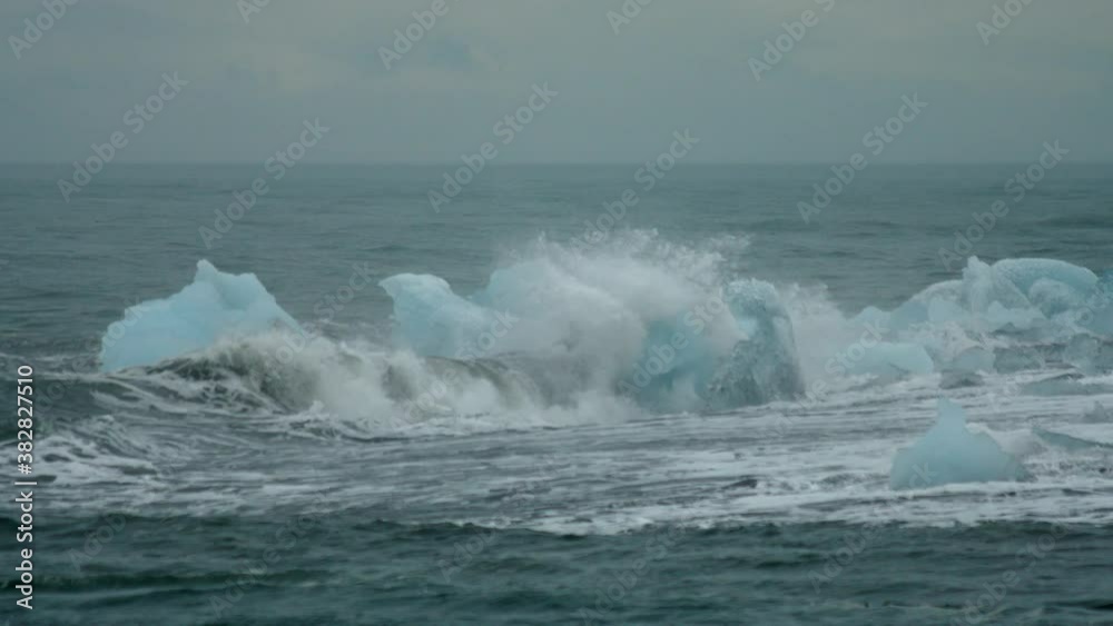 Wide, waves breaking on icebergs on a volcanic beach, Iceland Wide, waves breaking on icebergs on a volcanic beach, Iceland