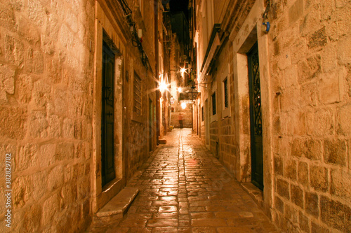 Narrow alley illuminated by street lamps at night in the old town of Dubrovnik, Croatia