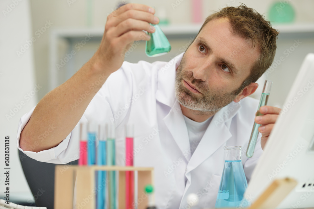 scientist holding small erlenmeyer flask up to the light scientist holding small erlenmeyer flask up to the light