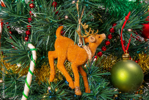 Close-up on the Christmas tree, its pretty garland in the shape of a deer and its barley sugar	