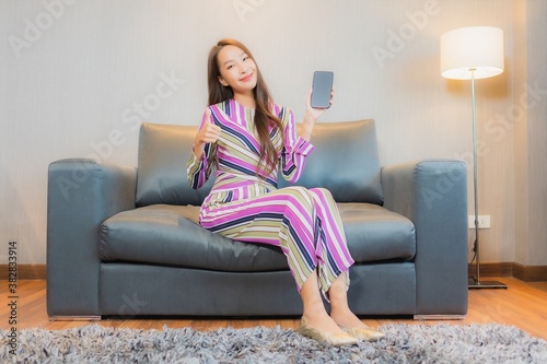 Portrait beautiful young asian woman use smart mobile phone on sofa © siraphol