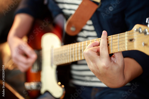 close up hand young man playing electric guitar at recording studio rehearsal base. rock music band.