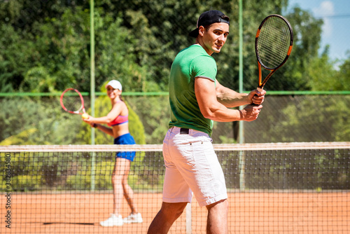 Young athletic couple playing tennis on the court.