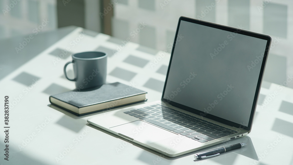 Mockup blank screen laptop with a keyboard on a table in co-workspace. Mockup blank screen laptop with a keyboard on a table in co-workspace.
