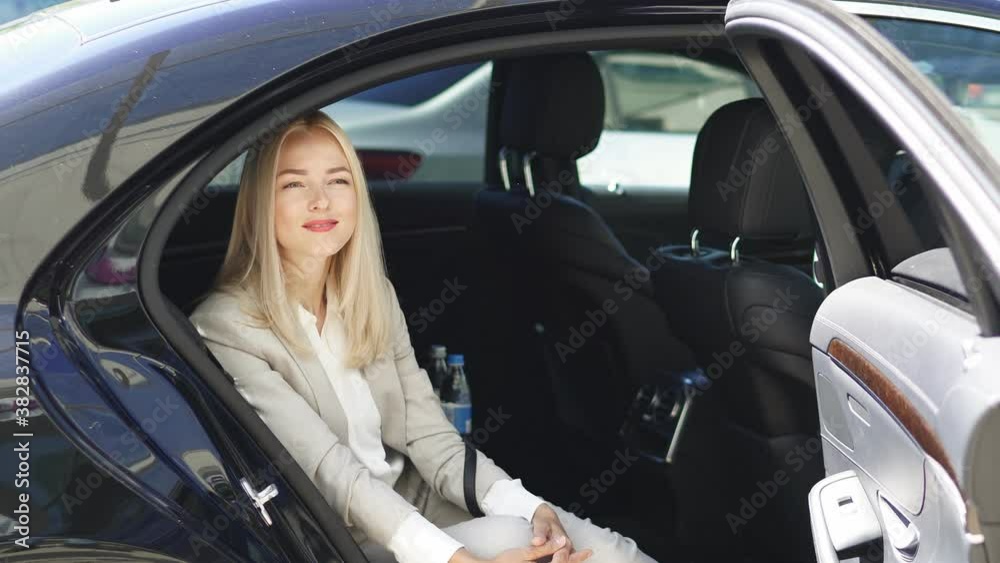 Attractive business lady sitting inside of luxurious car, waiting for personal private driver, business trip concept Attractive business lady sitting inside of luxurious car, waiting for personal private driver, business trip concept
