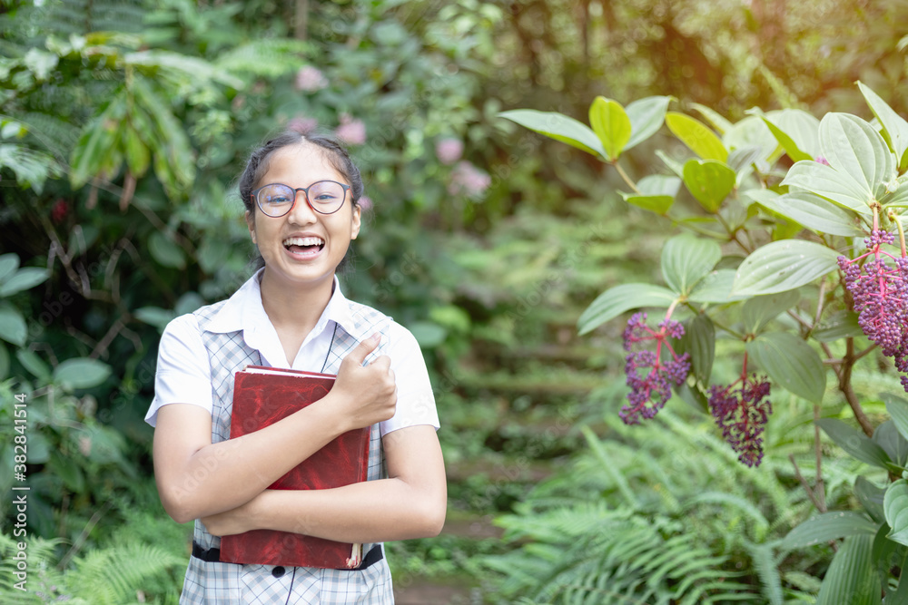 Confident Asian student girl with glasses holding book and smiling at camera Confident Asian student girl with glasses holding book and smiling at camera