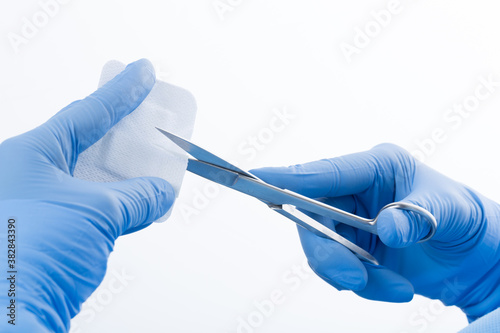 gloved hands cutting sterile bandage