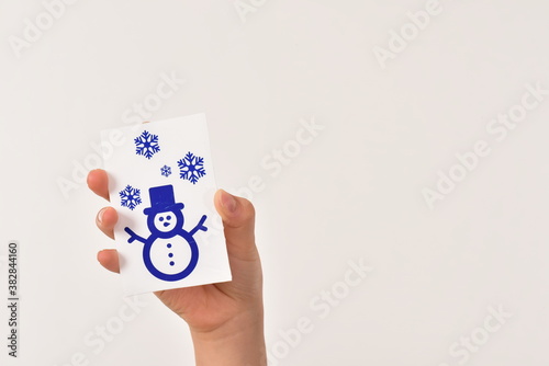 雪だるまマークのカードを高く上げている手 
