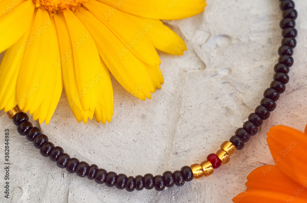 Handmade beadwork, beading as a hobby. Decorations made with your own hands on the background of various flowers Handmade beadwork, beading as a hobby. Decorations made with your own hands on the background of various flowers