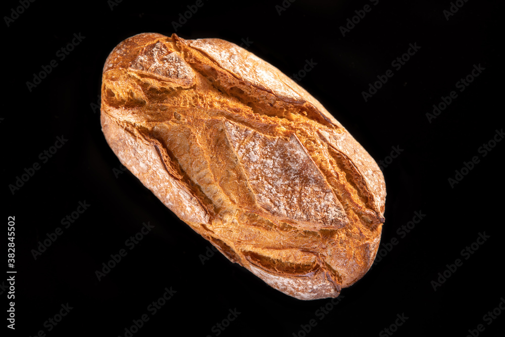 Rustic bread, beautiful golden crust with diamond patterns, top view, on black background	