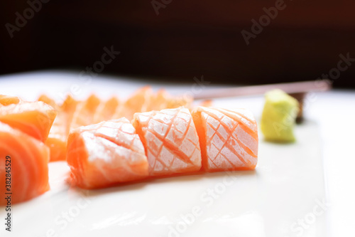 Fresh salmon and toro sashimi with shoyu and wasabi with chopsticks on mable plate. 