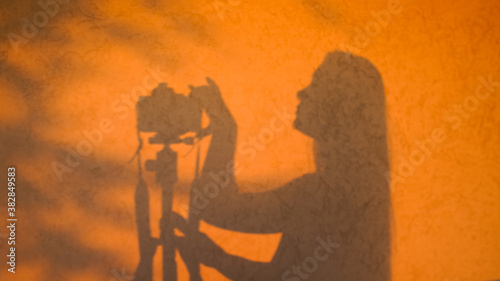 Silhouette of a photographer at sunset, on a wall in golden colors