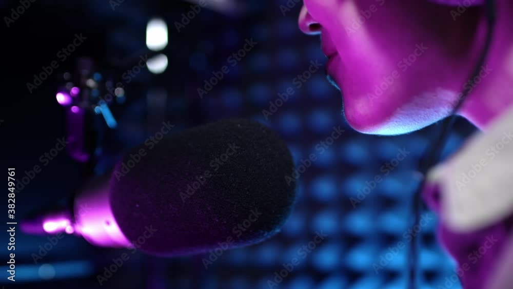 Beautiful young girl dj speaks into microphone, records podcast or morning news show for radio. Close up of podcast presenter or DJ talking on the microphone. Wears professional headphones Beautiful young girl dj speaks into microphone, records podcast or morning news show for radio. Close up of podcast presenter or DJ talking on the microphone. Wears professional headphones