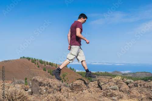 Young hiker jumping between rocks