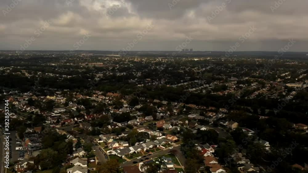 An aerial time lapse of a suburban neighborhood on a cloudy day. The drone tilts down from high up viewing the clouds. It tilts down and pan left while it dolly out over a suburb of Long Island, NY An aerial time lapse of a suburban neighborhood on a cloudy day. The drone tilts down from high up viewing the clouds. It tilts down and pan left while it dolly out over a suburb of Long Island, NY