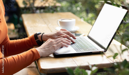 Cropped shot of young businesswoman working on her laptop while sitting outdoors at a cafe