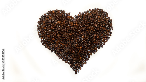 Roasted coffee beans, arranged in a heart shape, on white background	