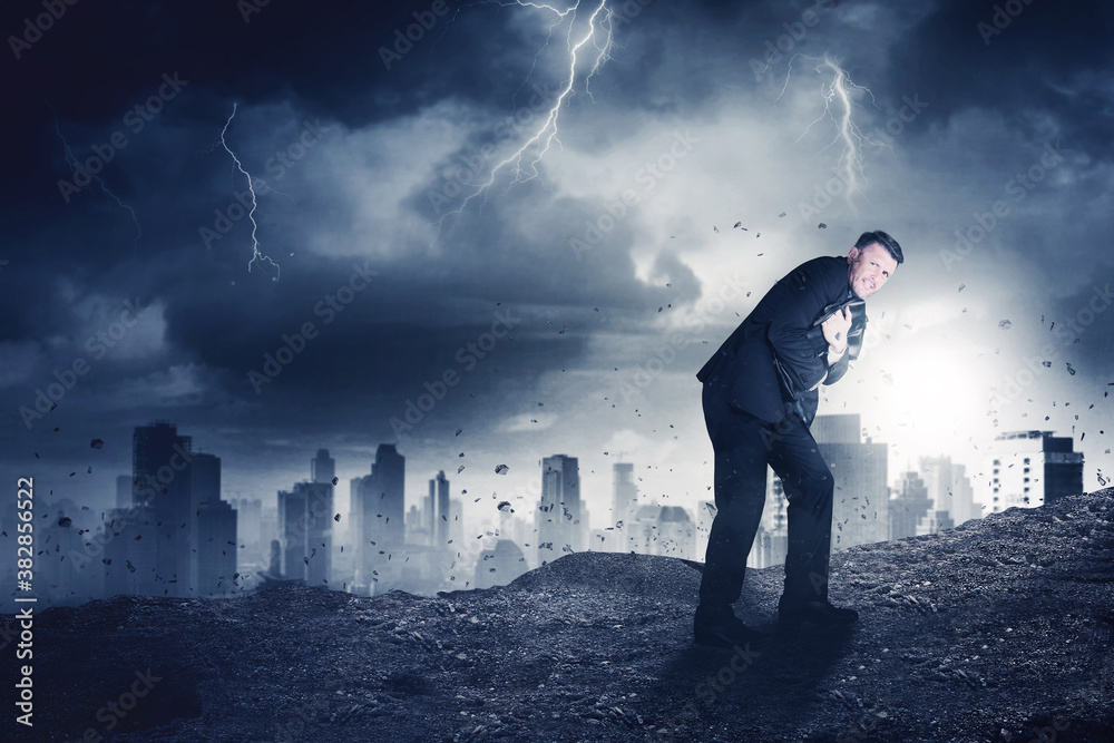 Scared manager embracing a suitcase in storm city Scared manager embracing a suitcase in storm city