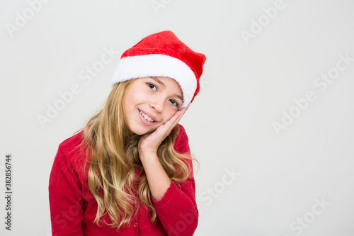 Dreamy young girl in red dress and santa hat isolated on white background  banner copy space. Christmas congratulation concept.