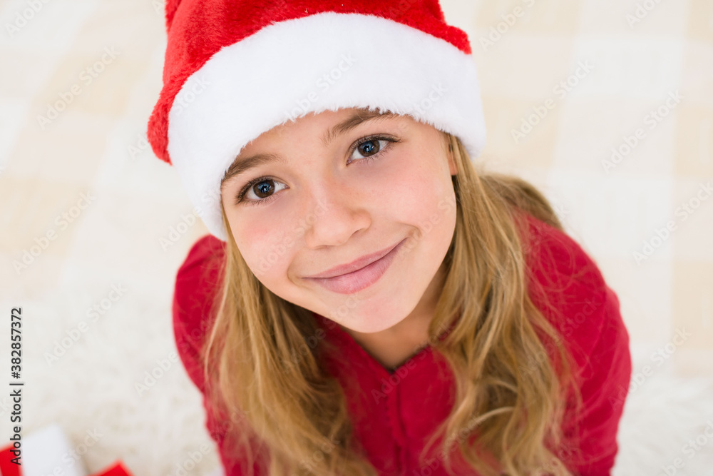 Young girl face in red santa hat with Child with Christmas concept, banner copy space. Top view. Young girl face in red santa hat with Child with Christmas concept, banner copy space. Top view.