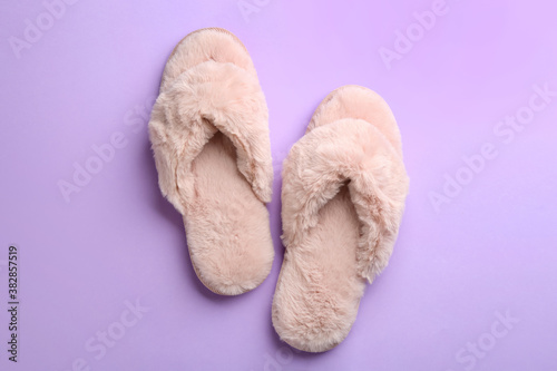 Pair of stylish soft slippers on violet background, flat lay