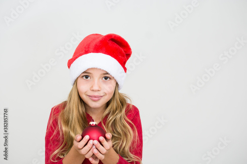 Young girl in red santa hat with christmas ball. Child with Christmas decoration  banner copy space. Isolated on white background.