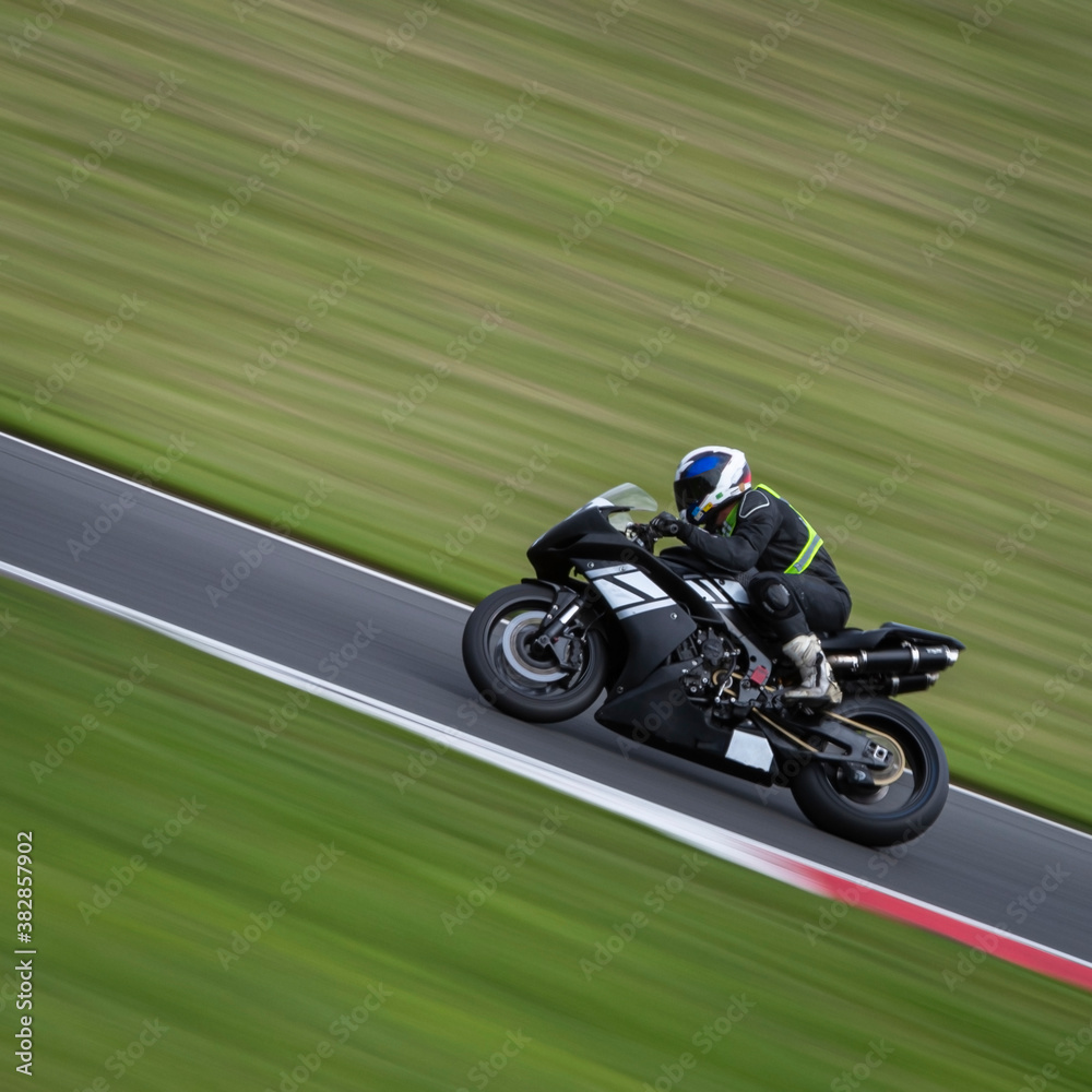 A panning shot of a racing bike cornering as it circuits a track.