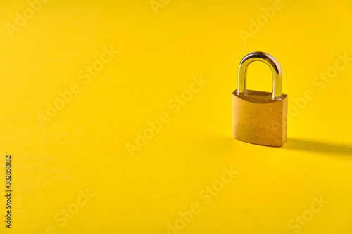 Small metal padlock on yellow background