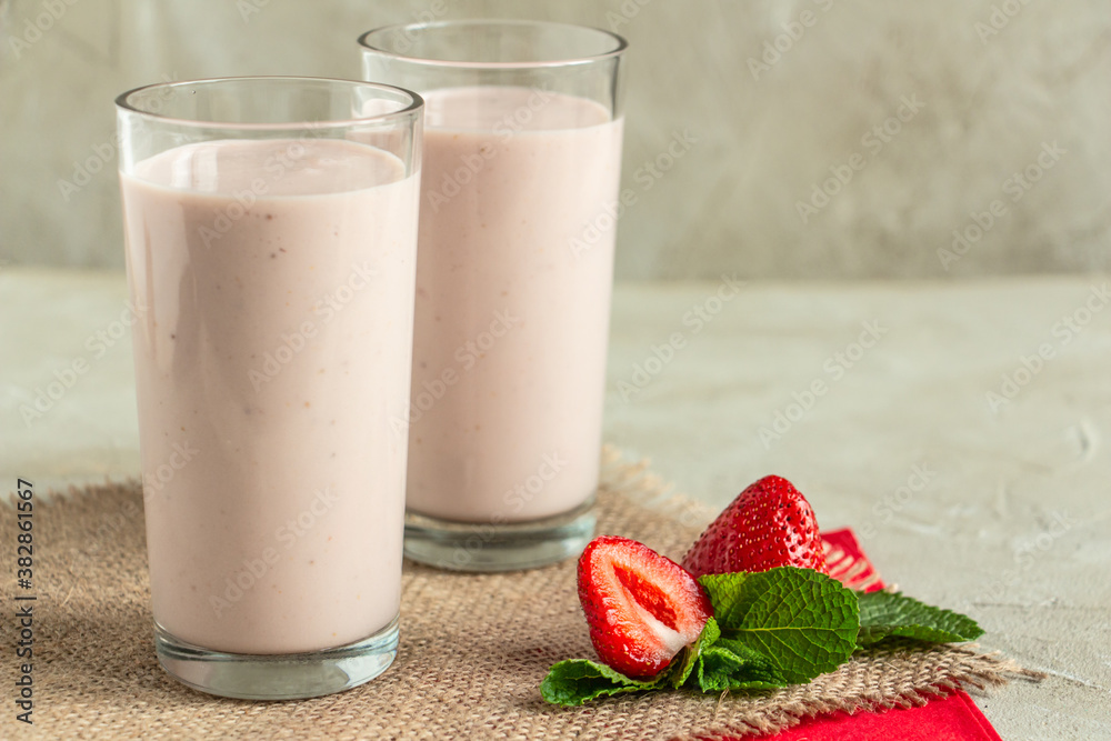 delicious milkshake with strawberries in tall glasses, strawberries and mint, burlap napkin create a cozy atmosphere delicious milkshake with strawberries in tall glasses, strawberries and mint, burlap napkin create a cozy atmosphere