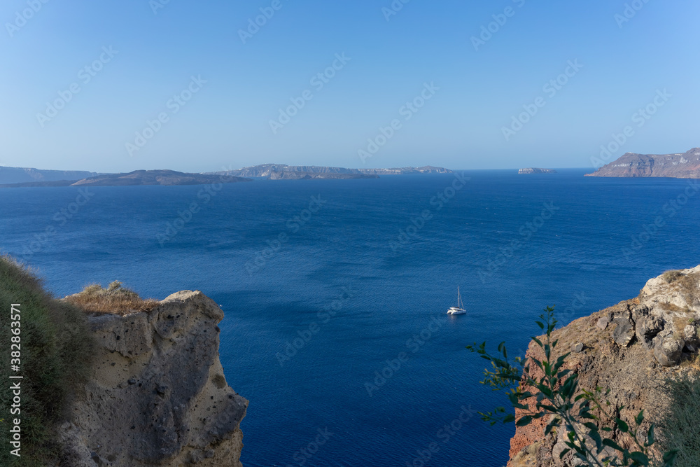 Beautiful panoramic view from Oia to caldera and volcano on a sunny day. Picturesque natural background with copy space for text. Santorini island, Cyclades, Greece, Europe.