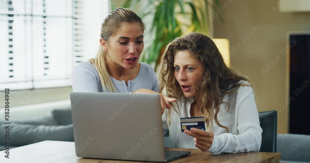 Authentic shot of young women girlfriends are entering credit card information by using a smart phone while making shopping online together in living room at home. Authentic shot of young women girlfriends are entering credit card information by using a smart phone while making shopping online together in living room at home.