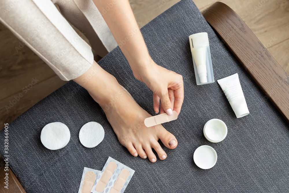 Foto de Subungual hematoma. woman gluing bandage on damaged toenail