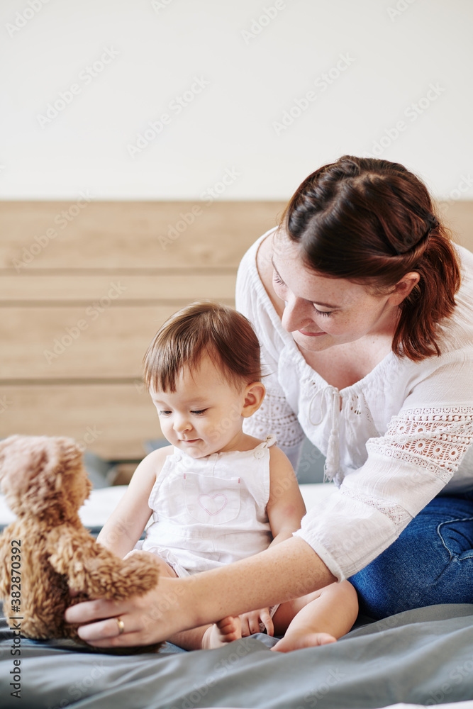 Young mother playing with her little baby girl on bed in the morning Young mother playing with her little baby girl on bed in the morning