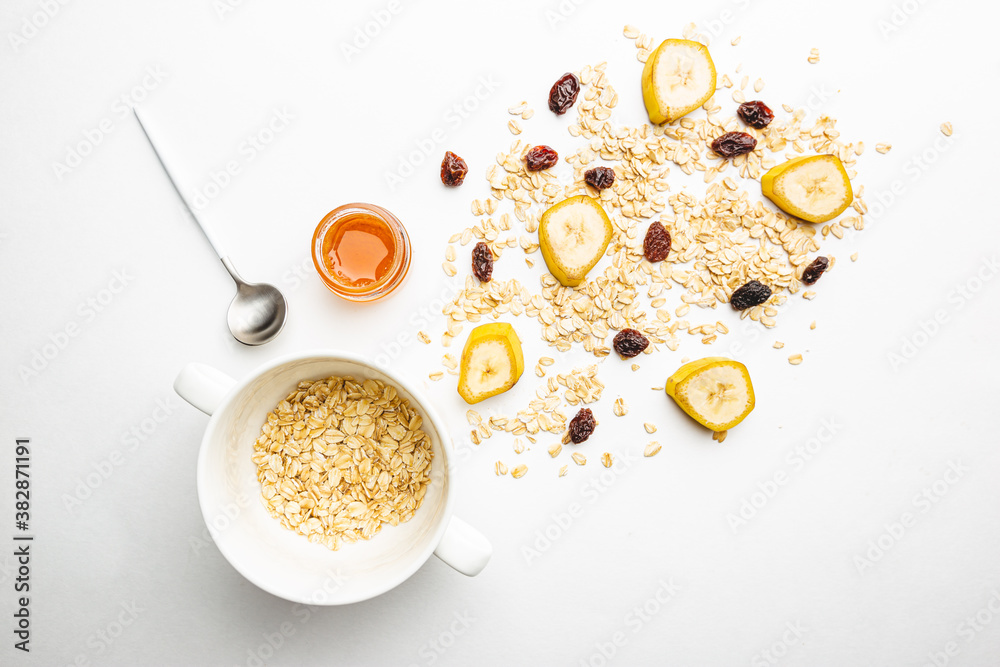 Bowl of oatmeal for porridge with ingredients banana, honey and raisins on white background, healthy breakfast every day, diet food