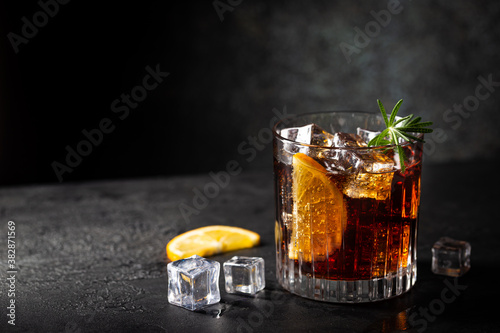 Obraz na plátně Fresh made Cuba Libre cocktail with brown rum, cola and lemon on wooden backgrou