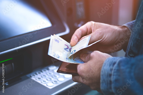 Unrecognizable man counting euros withdrawn from ATM. Man withdraws cash from bank. photo