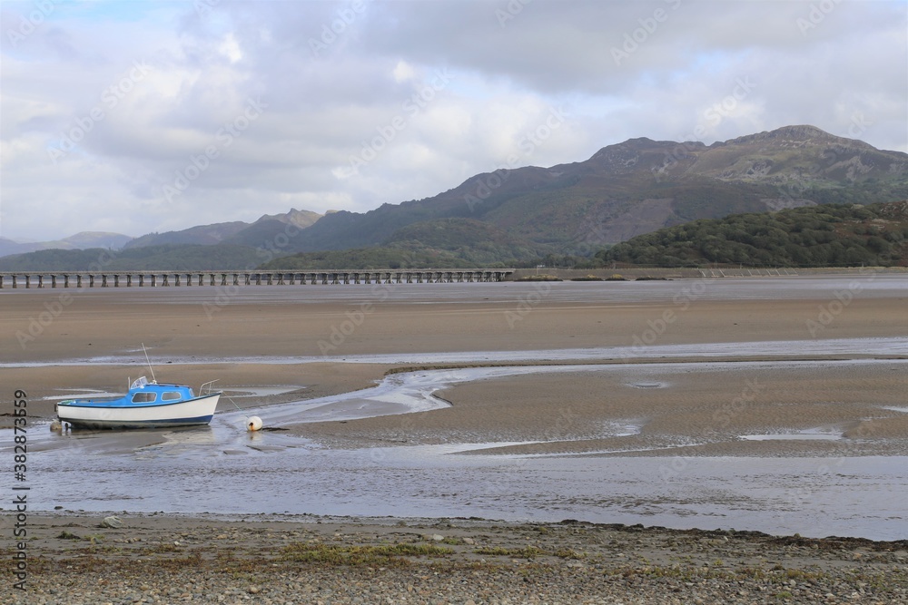 A coastal view of a boat in  the Mawddach Estuary with the tide out in Gwynedd, Wales, UK.