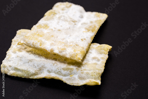 traditional sweet crisp pastry, deep fried for Carnaval, Italian chiacchiere on the black background