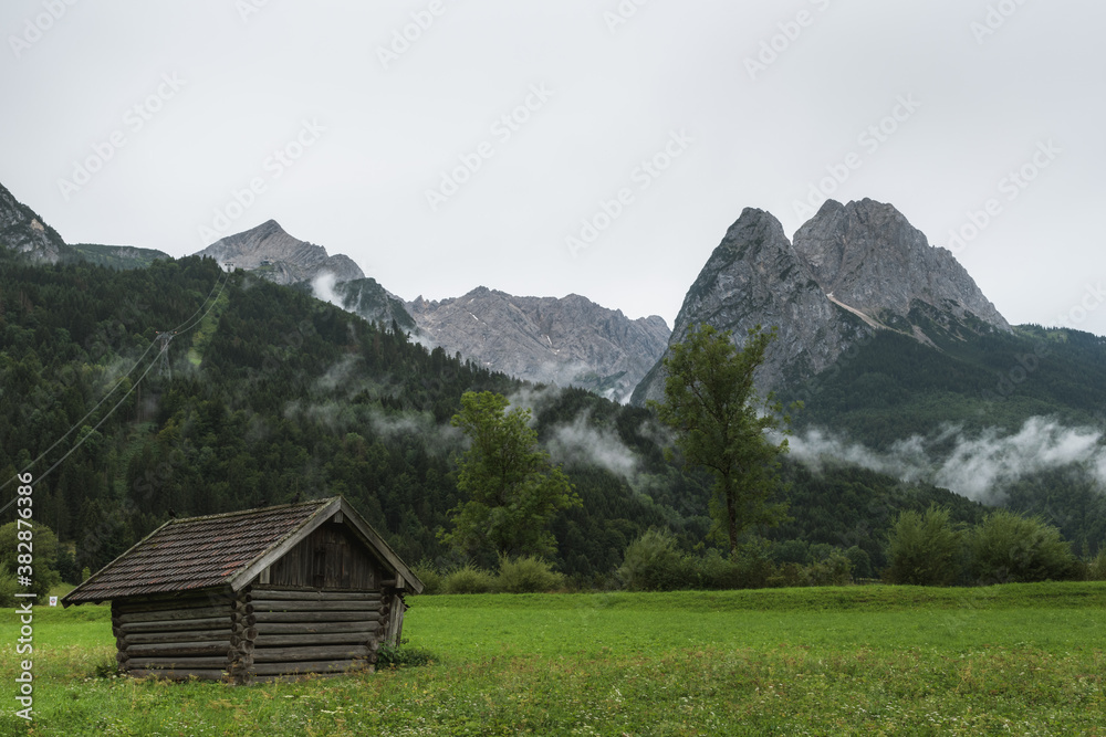 The Mountains Alpspitze and Waxenstein in the morning after the rain with a hut in the foreground. 