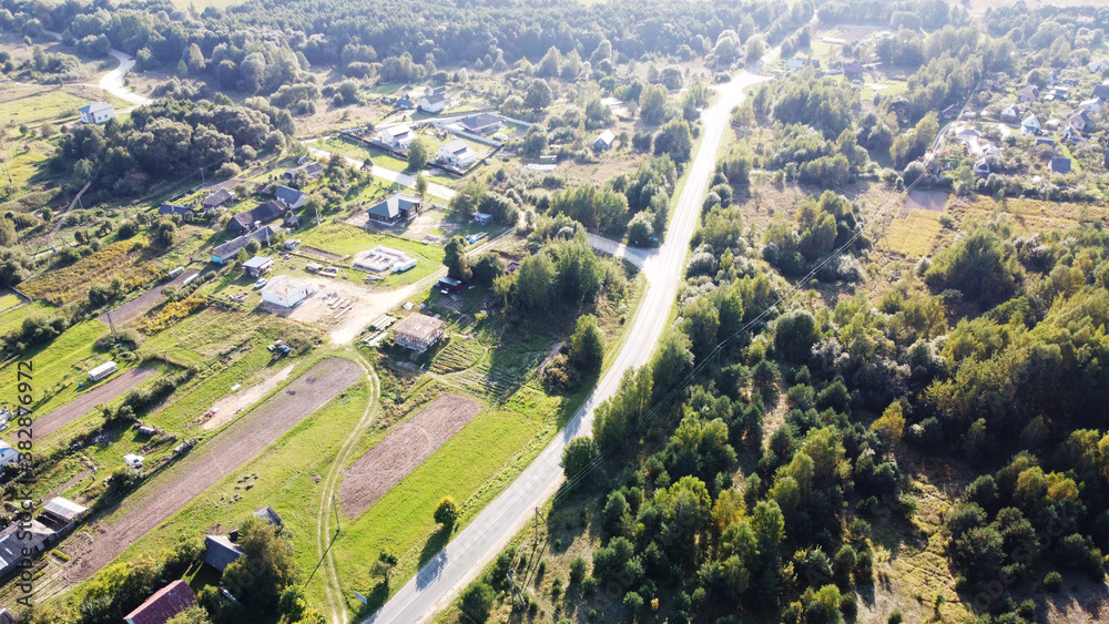 Top view of the highway near houses of a rural suburb on a sunny day