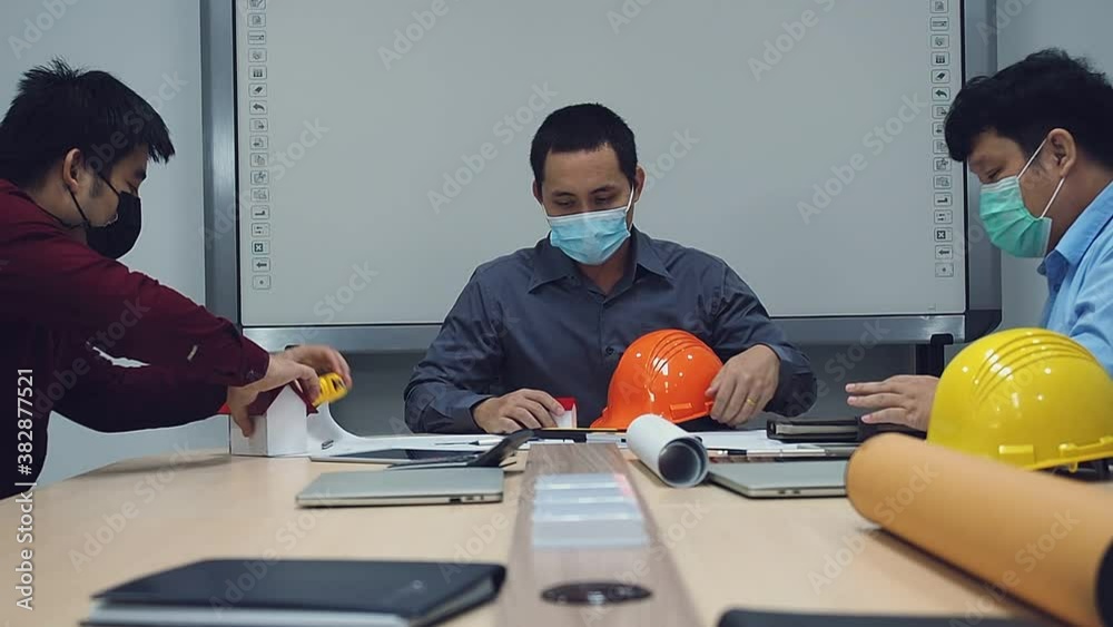 Confident team of architect and engineer wearing protective masks working together in a office. Social distance practice prevent coronavirus COVID-19. Confident team of architect and engineer wearing protective masks working together in a office. Social distance practice prevent coronavirus COVID-19.