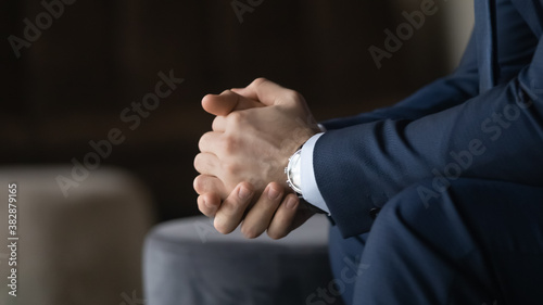 Obraz na płótnie Close up folded male hands, nervous stressed young businessman in suit thinking of difficult problem solution, need composure in making right decision, worrying manager feeling doubtful in office