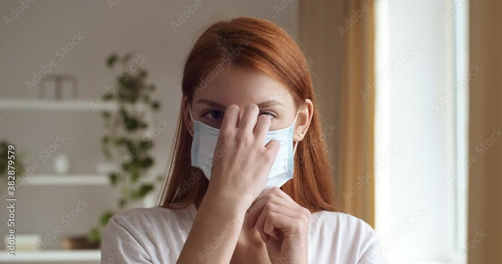 Portrait of confident redhead young girl teenager putting on medical mask on her face, covid virus pandemic epidemic outbreak concept. Responsible woman wears hygiene protector covering mouth and nose Portrait of confident redhead young girl teenager putting on medical mask on her face, covid virus pandemic epidemic outbreak concept. Responsible woman wears hygiene protector covering mouth and nose