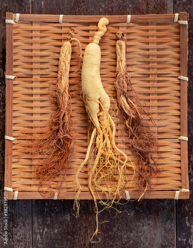 Fresh and dry ginseng on bamboo weave with copy space on the wood background photo