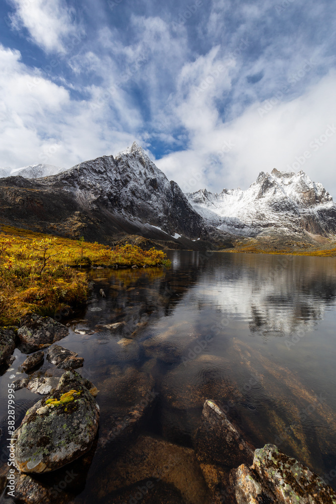 Beautiful View of Scenic Alpine Lake, Rocks and Snowy Mountain Peaks in Canadian Nature. Season change from Fall to Winter. Taken at Grizzly Lake in Tombstone Territorial Park, Yukon, Canada.