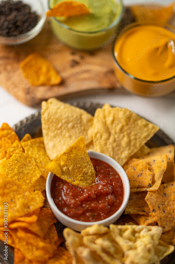 Close-up of traditional mexican corn tortilla chips with salsa and cheese dip. Tasty meal. Food concept. White background. Close-up of traditional mexican corn tortilla chips with salsa and cheese dip. Tasty meal. Food concept. White background.