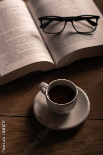 Cup of coffee and a book on a wooden table