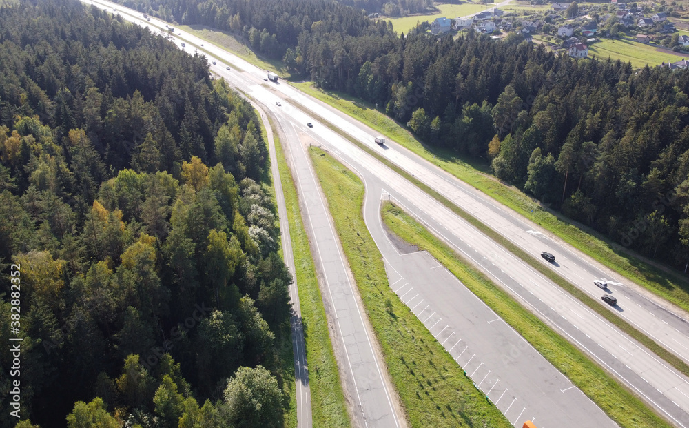 Top view of the long highway autobahn with cars through the forest