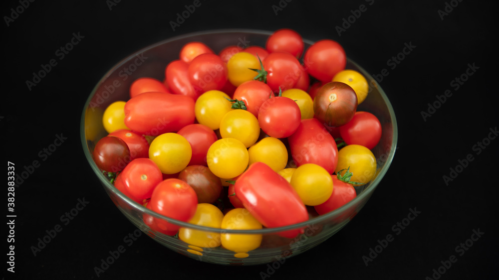 Small cocktail tomatoes, multicolored, round and oval, in a transparent glass container, on black background, close-up
Small cocktail tomatoes, multicolored, round and oval, in a transparent glass container, on black background, close-up
