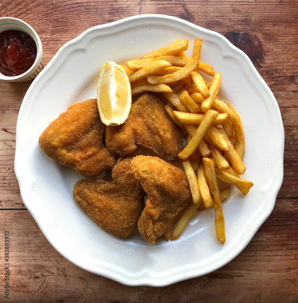 Breaded chicken wings, also known as breaded fried chicken wings are coated in egg, flour and breadcrumbs, then deep fried to golden brown and served with french fries, ketchup and lemon. Breaded chicken wings, also known as breaded fried chicken wings are coated in egg, flour and breadcrumbs, then deep fried to golden brown and served with french fries, ketchup and lemon.